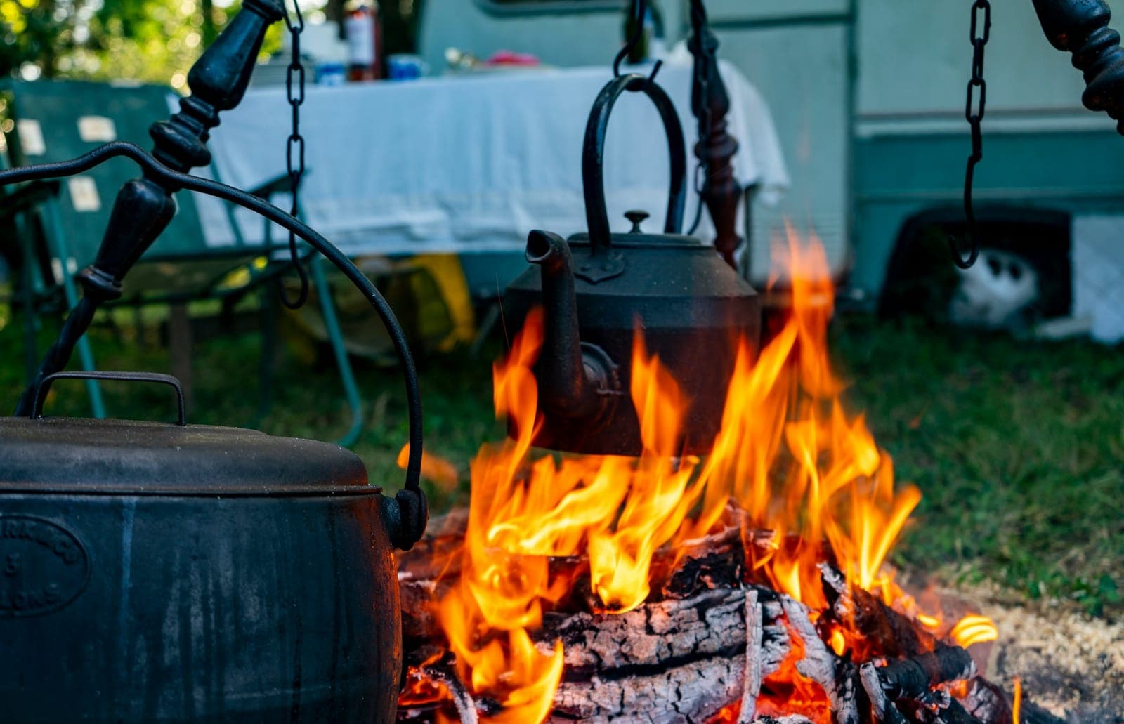 Cast iron pots and a kettle cooking over a campfire